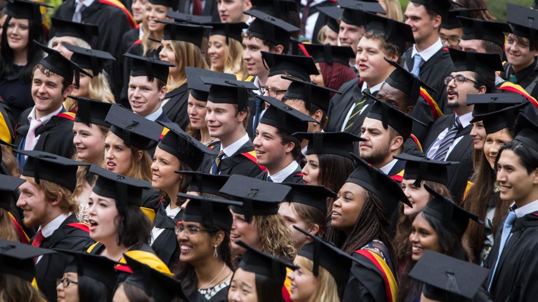 Students in their cap and gowns celebrating after their graduation ceremony