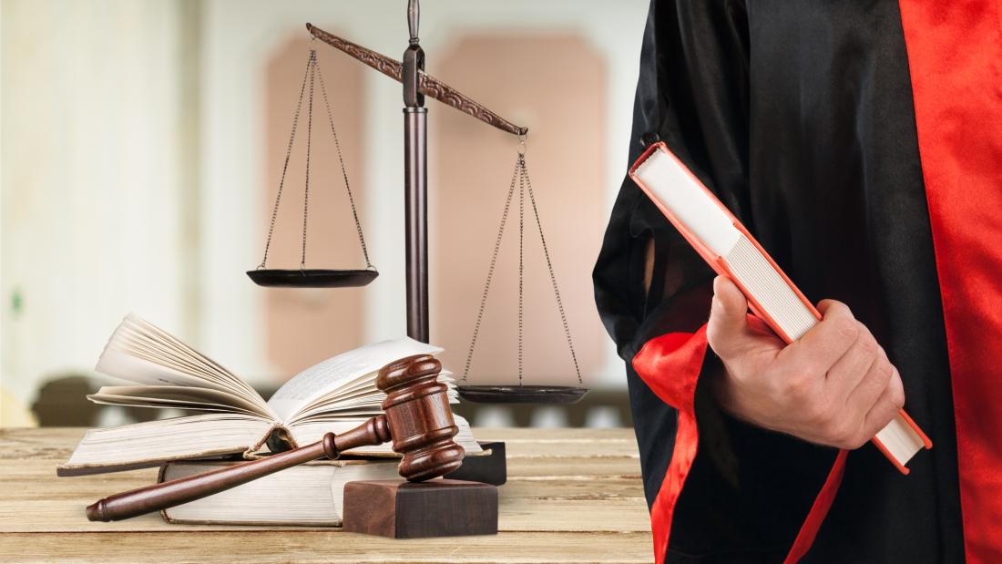 Image of Law student in robe with scales in background