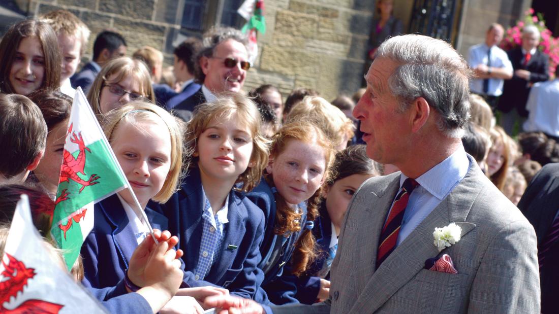   Tywysog Siarl yn siarad efo plant sygol sy'n cwifio'r Ddraig Goch, yn ystod ymweliad â Phrifysgol bangor yn 2009