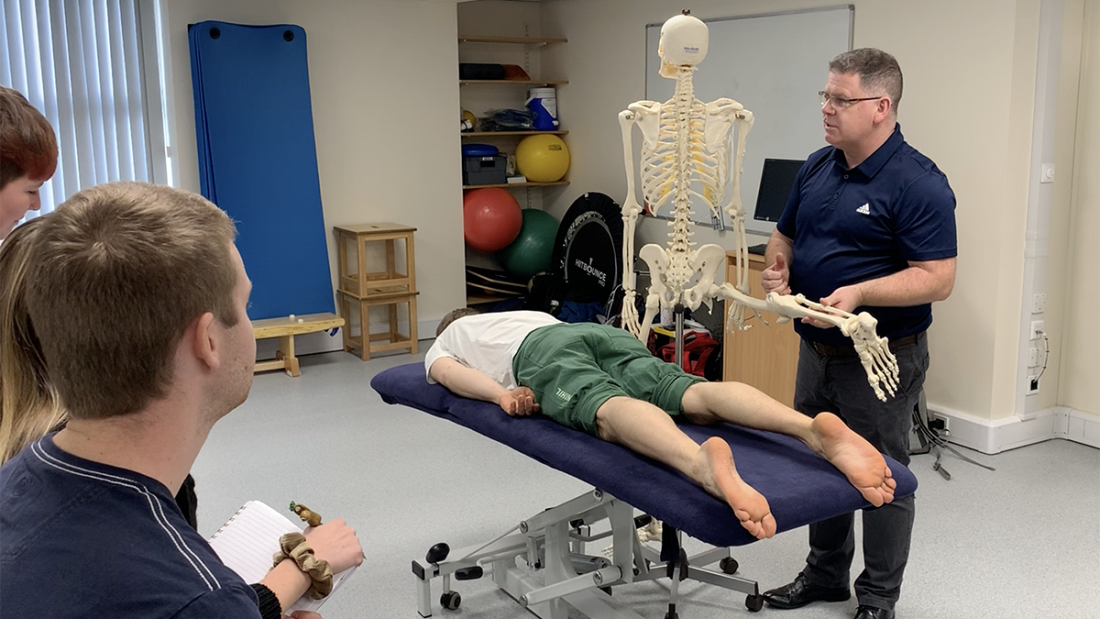 Lecturer Jonathan Flynn in class holding a skeleton during a practical