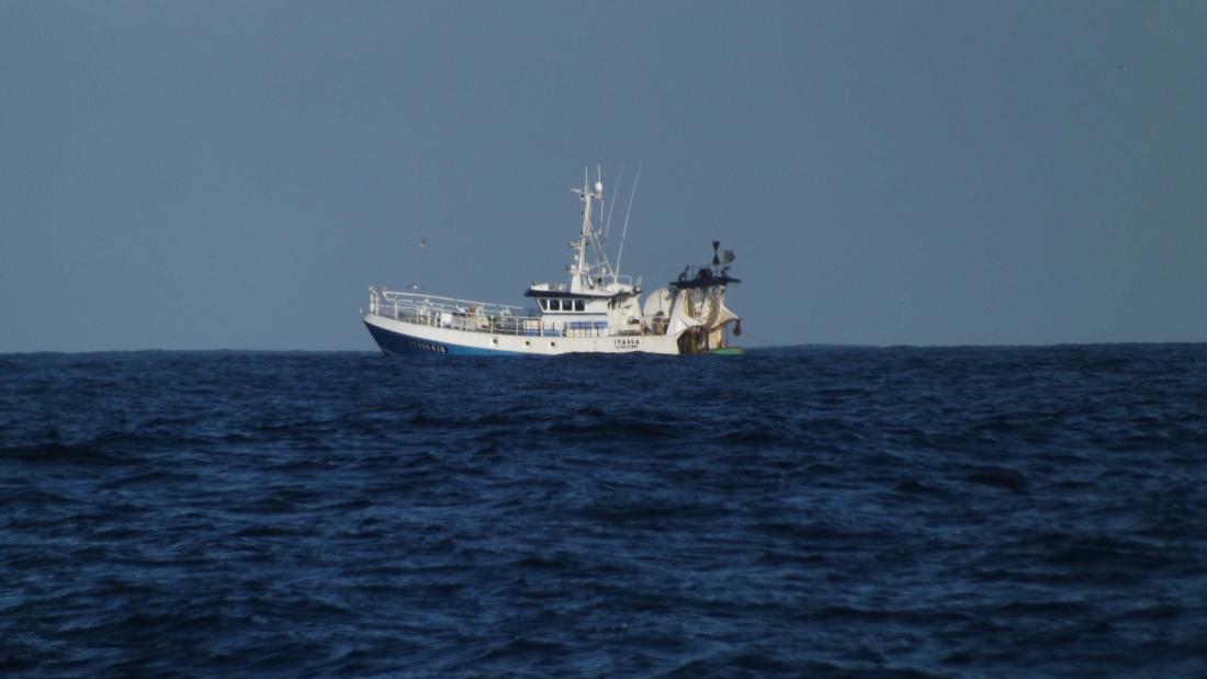 A trawler sits on the horizon