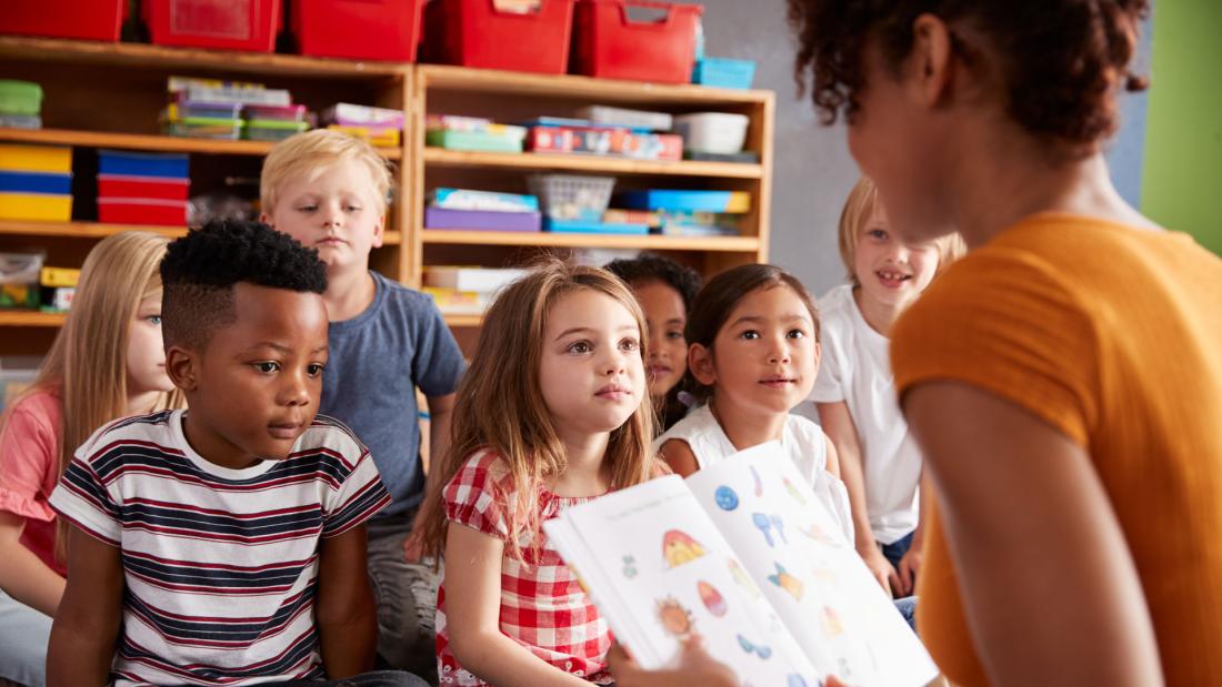 Group of primary school children sat listening to the teacher in a classroom