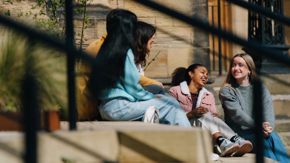 Group of students sitting on some steps talking 