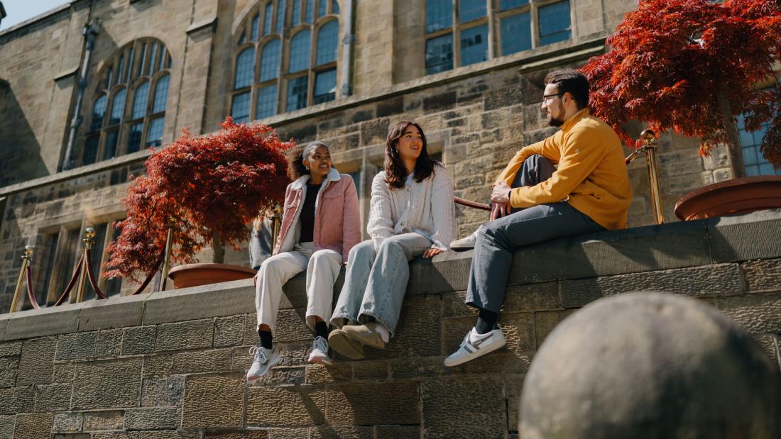 Group of students talking sitting in the inner quad of the Main University Building