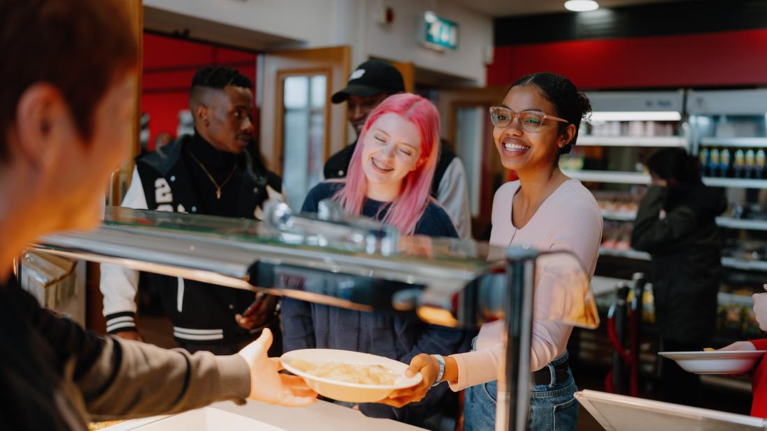 A group of students being served food at a counter in Teras Café