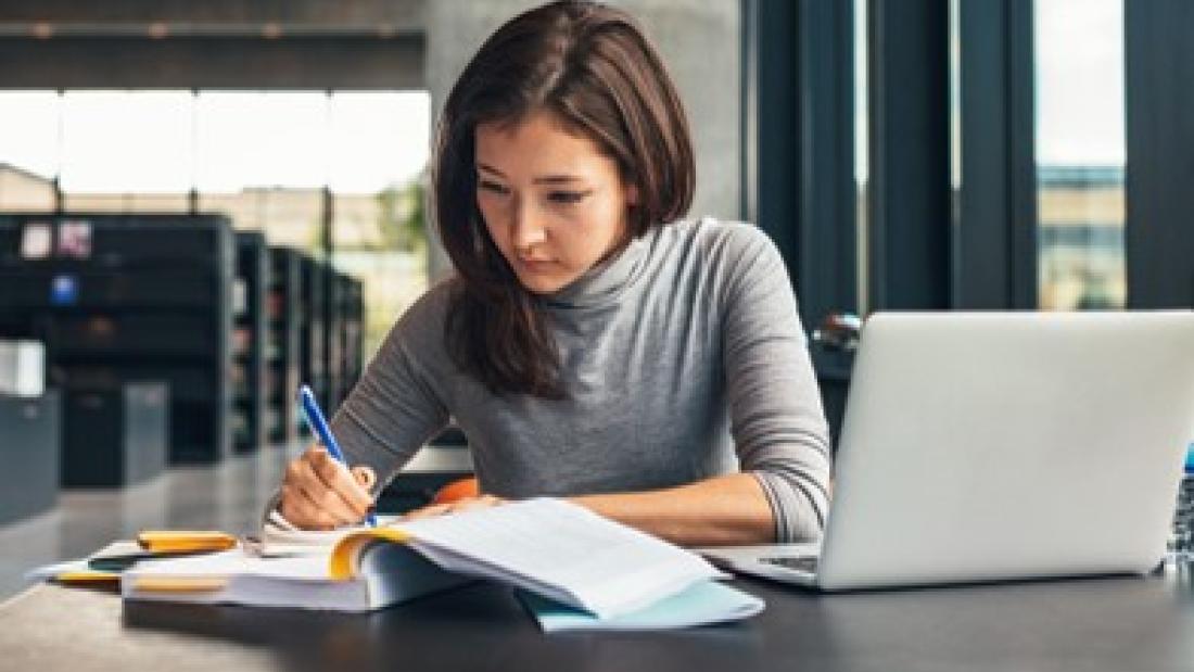 Student studying with laptop and textbook