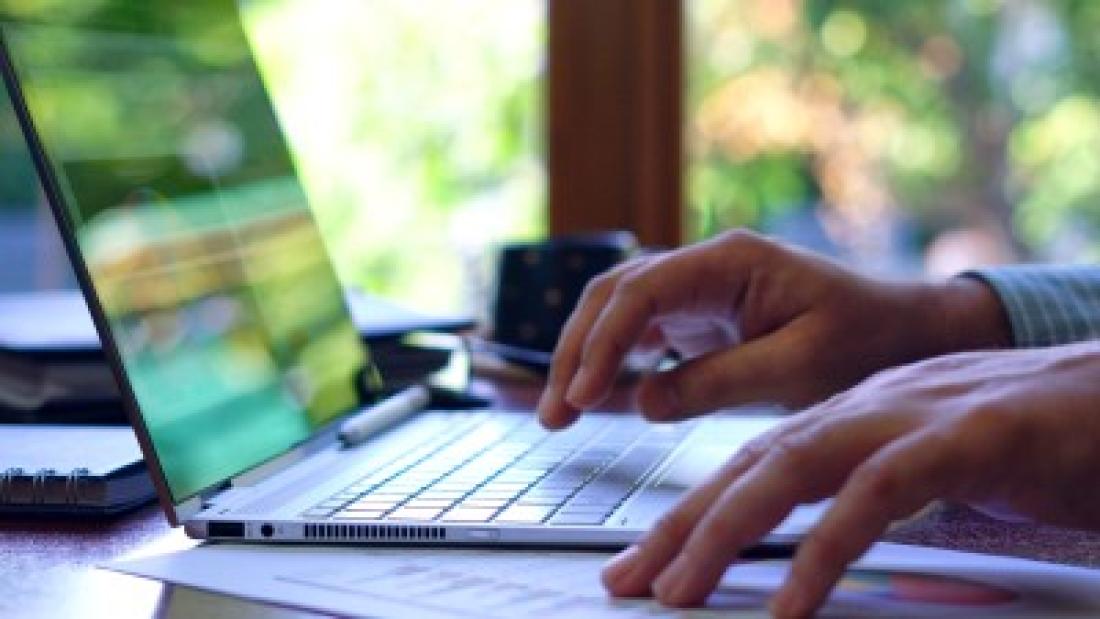 Hands typing on a laptop