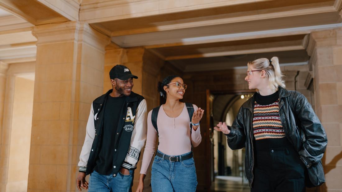 A photo of three students walking through the corridor of Main Arts.