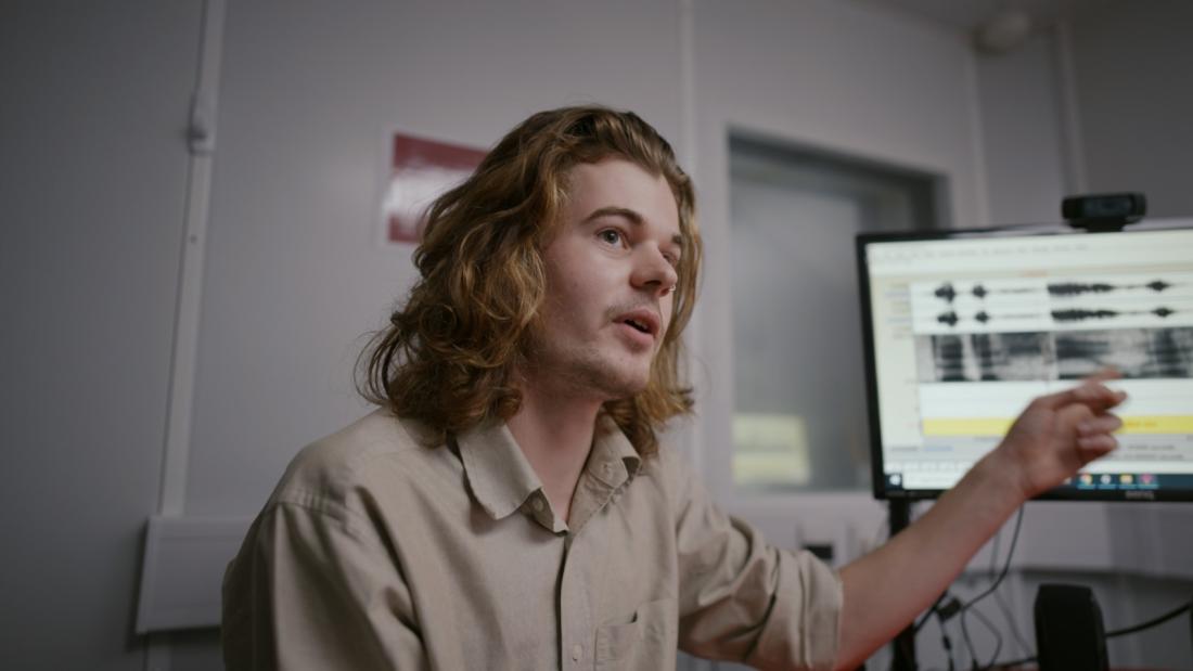 Student pointing towards sound bars on computer screen