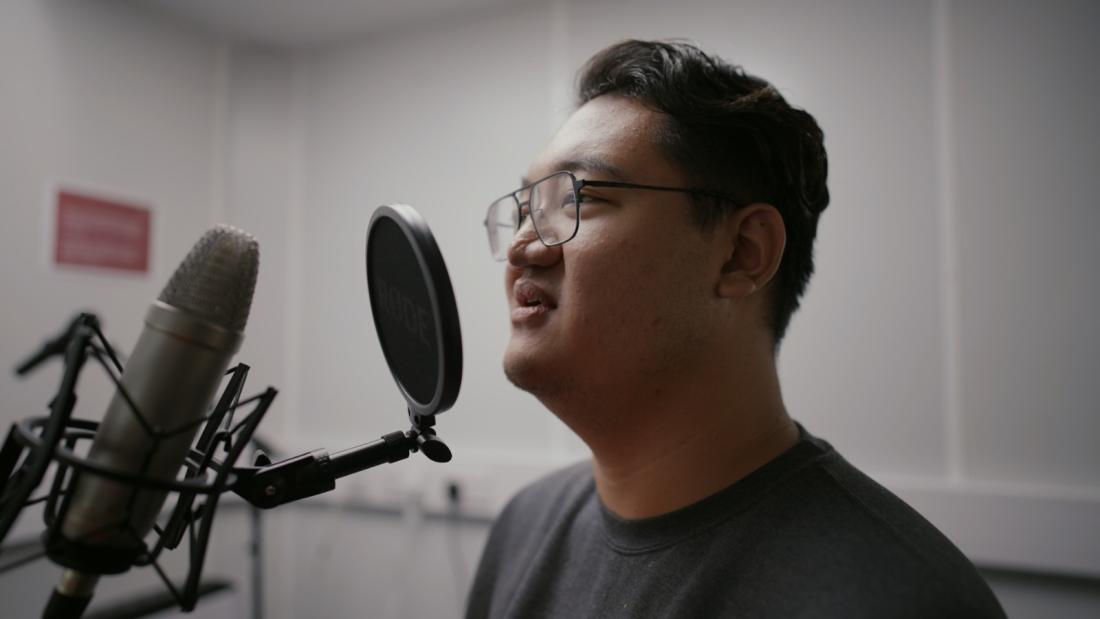 Student speaking into microphone in phonetics lab