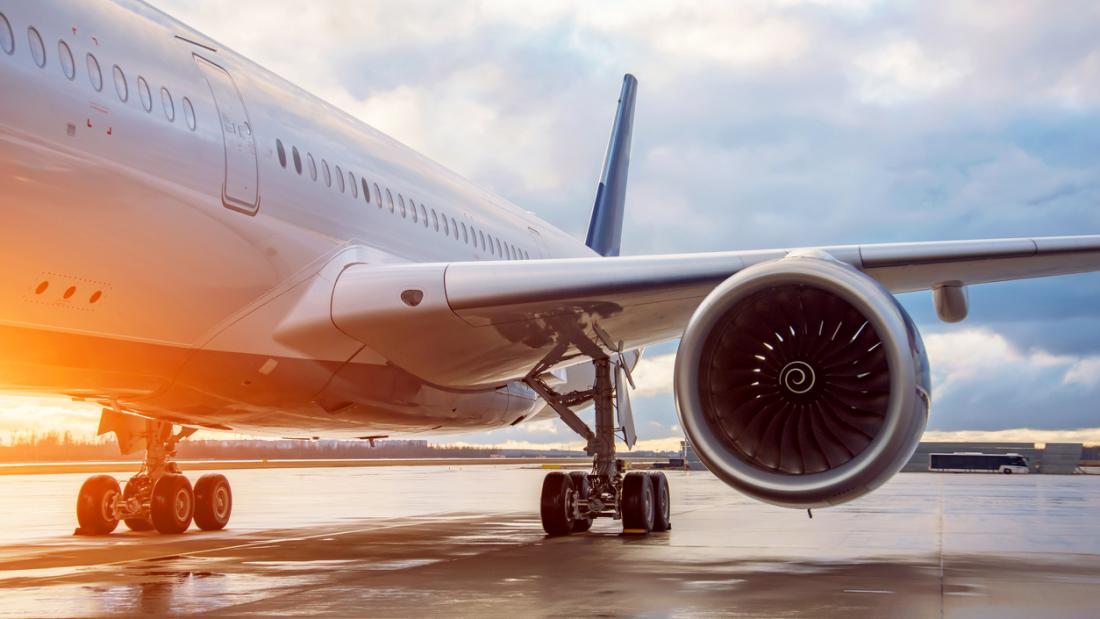 Fuselage of a passenger wide-body airliner, view of the landing gear of the engine and wing in the evening during the evening light of the sun