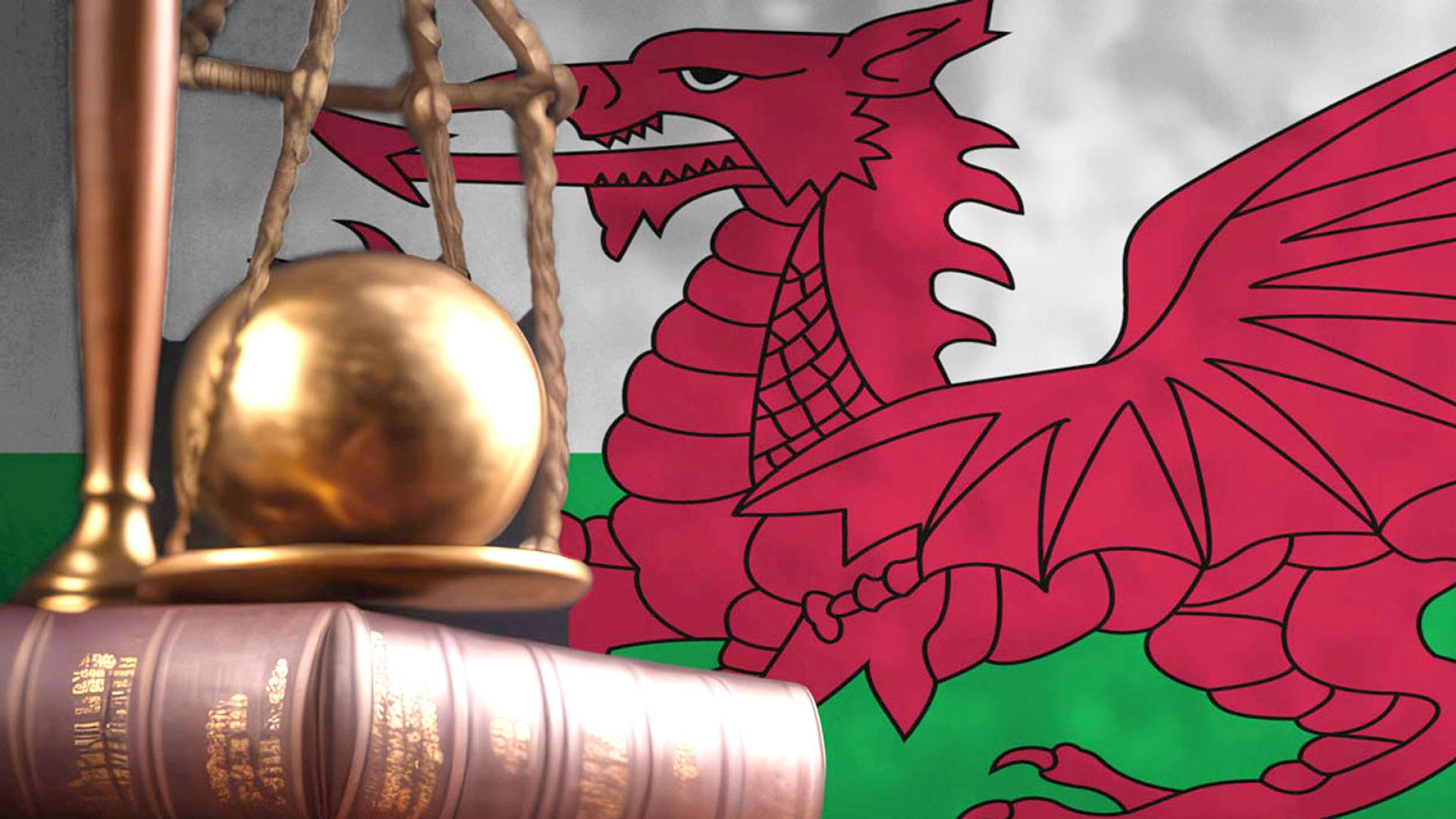 Law books on table with Welsh flag on the wall behind