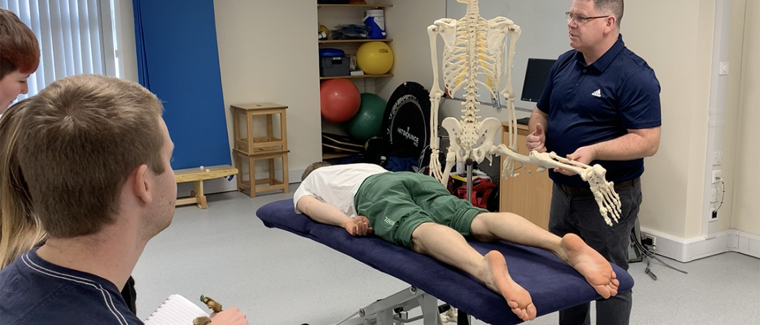 Lecturer Jonathan Flynn in class holding a skeleton during a practical