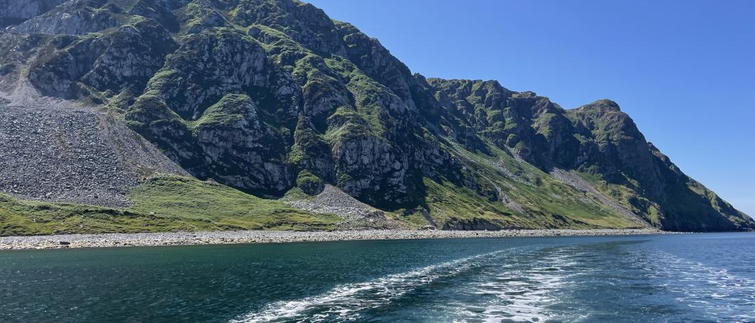 Rocky cliffs seen from the stern of a boat 