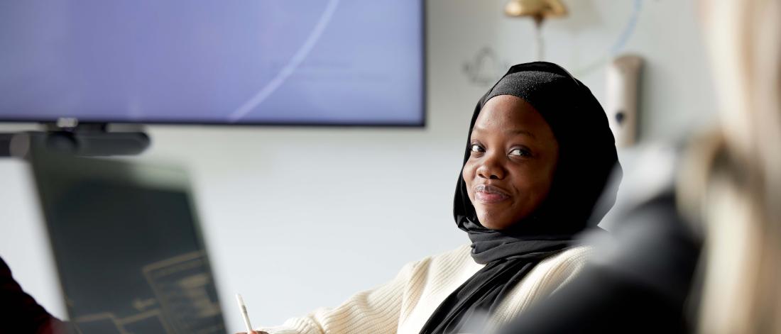 Fatima smiling to camera in boardroom 