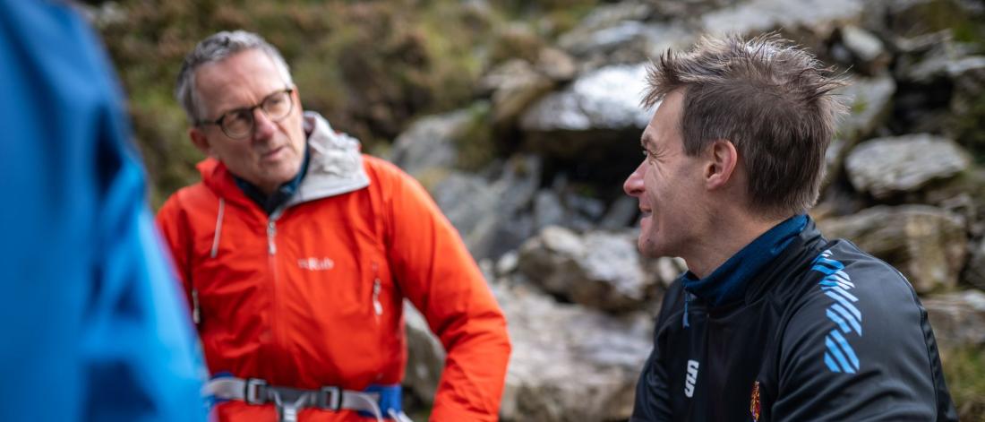 Two men, Michael Mosley with Professor Jamie Macdonald, sitting on the side of a mountain with climbing gear