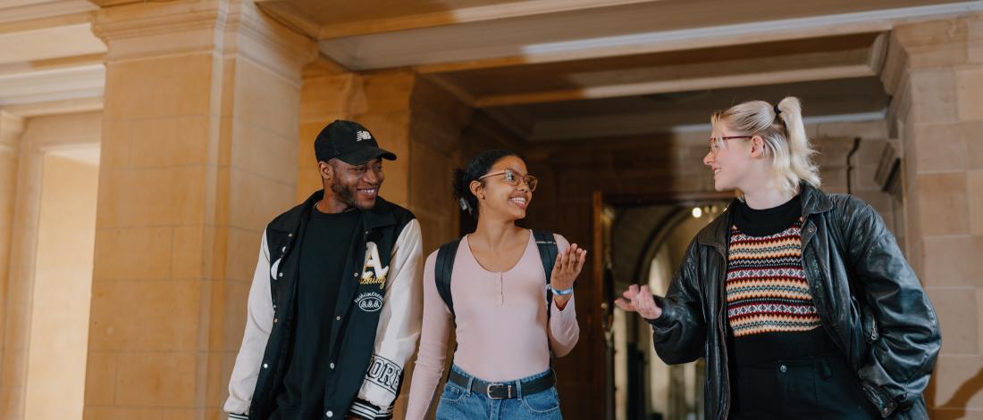 A photo of three students walking through the corridor of Main Arts.