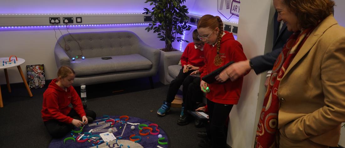 Welsh First MInister watching children play a game on a mat 