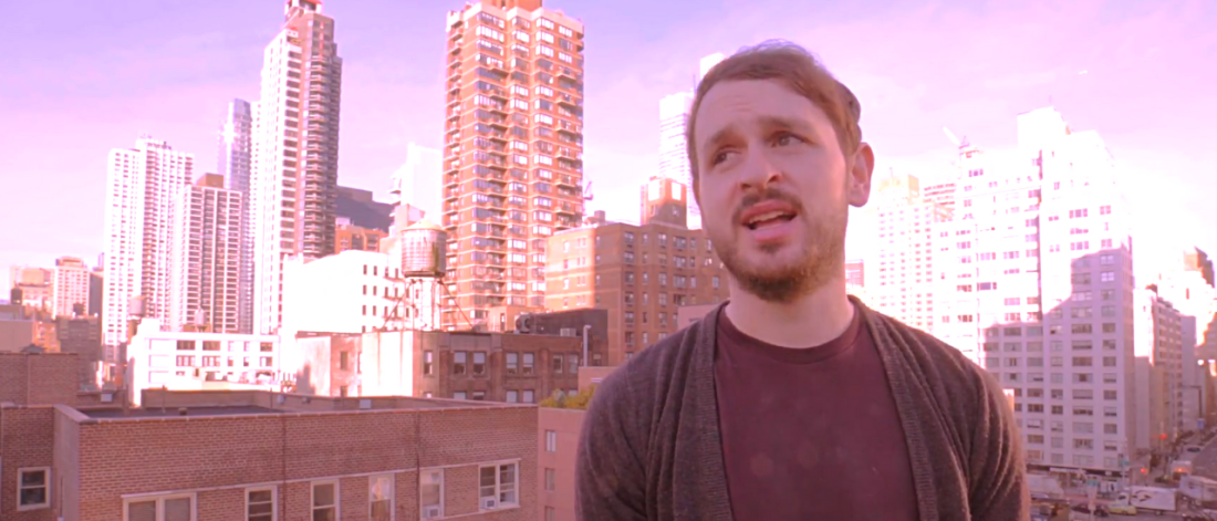 Image of Bangor graduate Osian Williams standing in front of high rise buildings