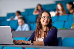 A student taking notes on her laptop in a lecture