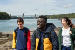 Students walking with the Britannia Bridge in the background