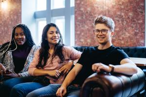 Three students relaxing on the sofas in Barlows at the St Mary's Student Village