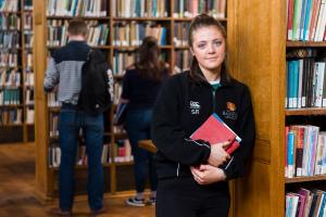 A student carrying books in the Shankland Library