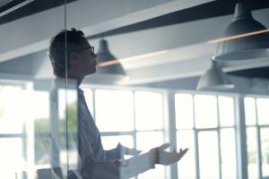 Man standing in a modern looking room with glass giving speach