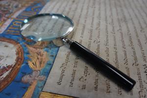 Photo of a colourfula archival manuscript with a looking glass on it.