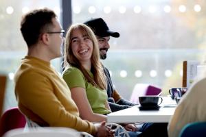 Students sitting in the pontio cafe drinking coffee and laughing together