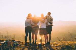 a group of people hugging outside looking at the sunny scenery 