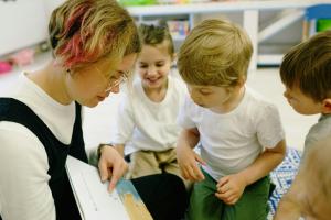 Three kids with a teaching reading a book 