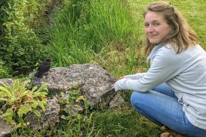 Dr Svenja Tidau kneeling by a rock looking at a bird