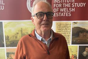 Doctoral Researcher Hugh stands in front of an ISWE banner. 