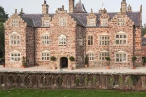 Plas Coch, a redstone mansion with a symmetrical facade, crow-stepped gables, and pediments above each window. 