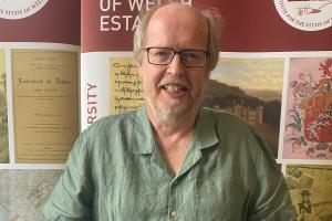 Doctoral Researcher Jeff stands in front of an ISWE banner. 