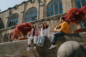 Three students sitting on the wall in the inner quad, Main Arts Building