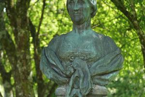 Photograph of a statue of a woman mounted in a woodland.