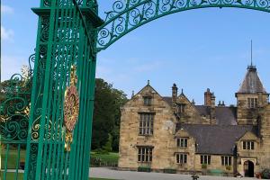 A country house with an ornate green and gold gateway in the foreground.