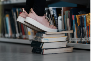 Picture of someone standing on a stack of books with pink shoes