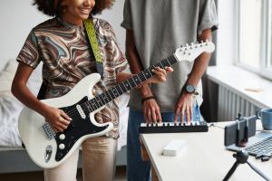 Music & Media Studies students recording instruments whilst recording and filming themselves on a computer