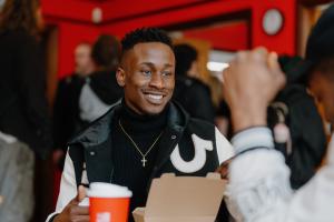 A student eating food and socialising at a table in Teras Café