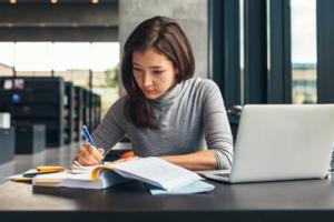 Student studying with laptop and textbook