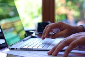 Hands typing on a laptop