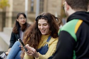 Student showing her mobile phone with friends