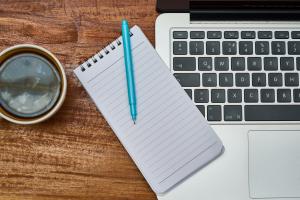 Image of coffee cup notebook and laptop on a table