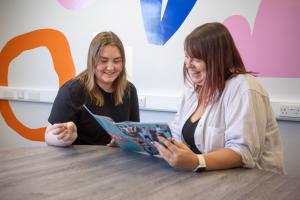 Two women smiling looking at a brochure