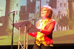 Marian Gwyn presenting in front of an image of Penrhyn Castle.