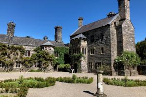 Photograph of Gwydir Castle, a stone mansion with a blue sky in the background. 