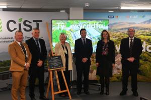 6 people standing in behind a plaque for the ppening ceremony of Ty Gwyrddfai 